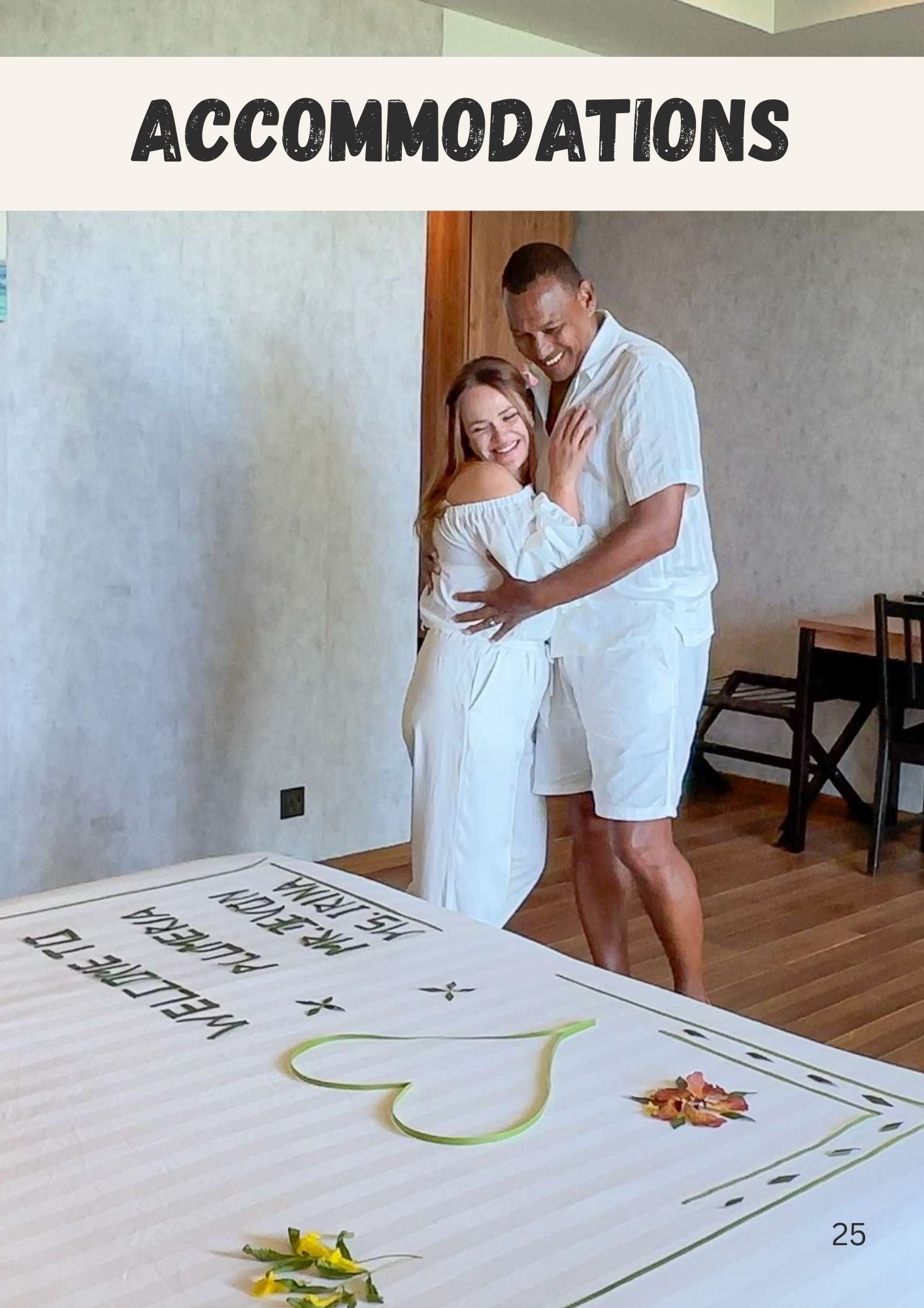 Couple in matching white outfits smiling beside decorated bed at Plumeria Hotel in Thinadhoo Maldives